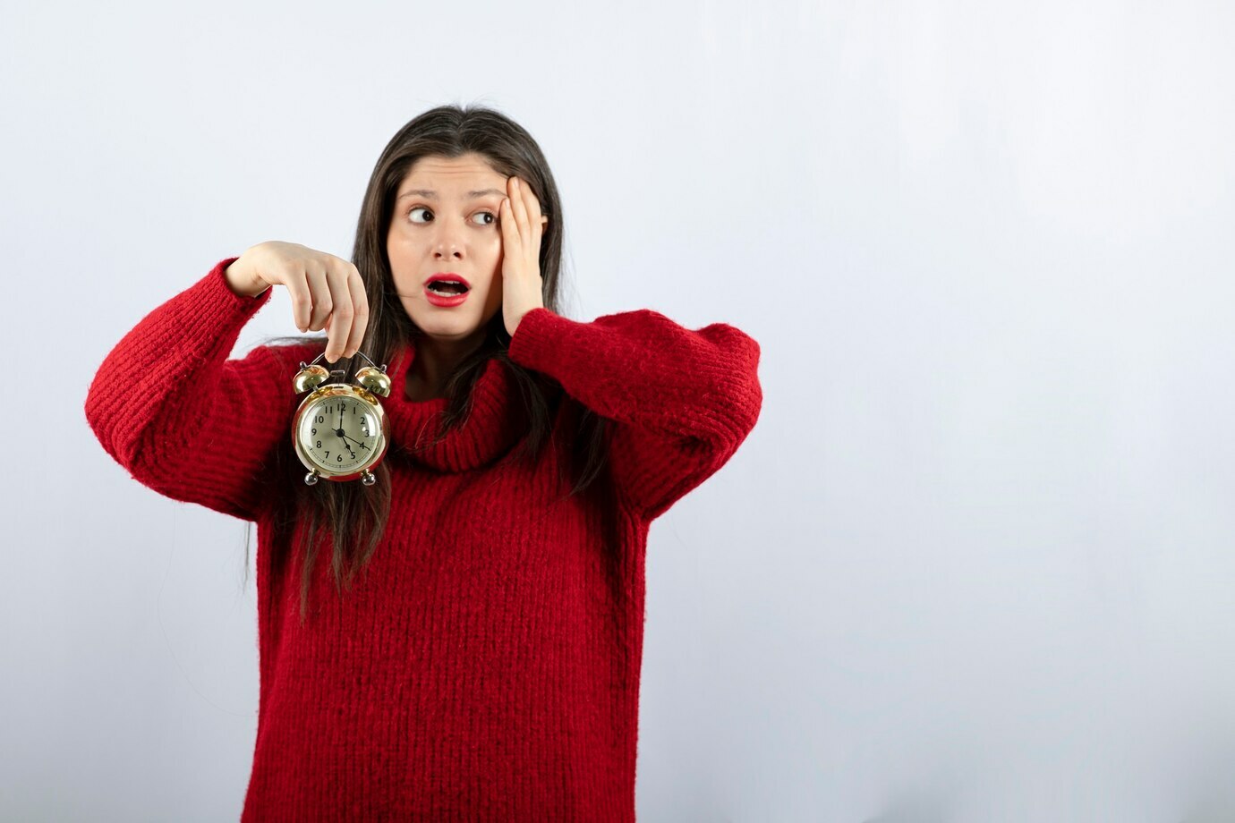 linda-morena-jovem-segurando-um-despertador-em-pe-sobre-um-fundo-branco_114579-65781